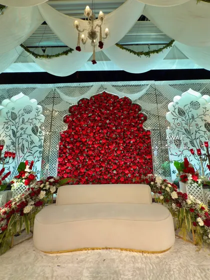 The central focus of the stage, with a plush cream sofa set against a stunning archway completely filled with deep red roses.