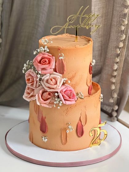 Celebrating 25 years of love with a cake that is both elegant and romantic. This two-tier design features peach buttercream, hand-piped textures, and a cascade of blooming pink roses.