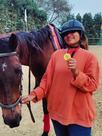 A close-up of a student and her horse, showcasing the medal earned for her hard work and dedication in her riding lessons.