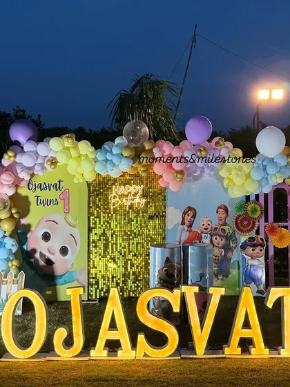 A closer view of Ojasvat's Cocomelon stage, featuring a gold sequin backdrop, a pastel balloon arch, and large marquee letters.