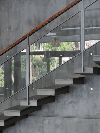 A detail of the cantilevered concrete stairs against an exposed concrete wall. The raw, honest expression of the structure is a key part of the home's aesthetic.