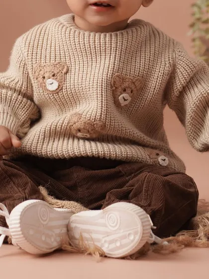 A detail shot from the academic-themed session, focusing on the baby's adorable teddy bear sweater and corduroy pants.