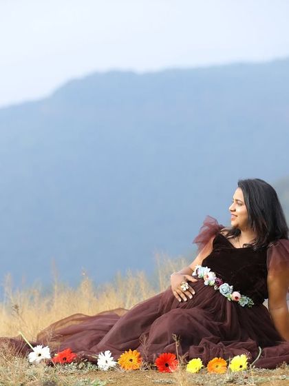 A creative and colorful maternity shot. The dark ruffled gown is accessorized with a floral belt and a line of fresh flowers, adding a personal and beautiful touch.
