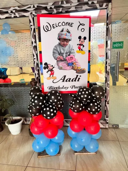 A personalized welcome sign for Aadi's Mickey Mouse party, flanked by balloon pillars in the theme's signature red, blue, and polka-dot style.