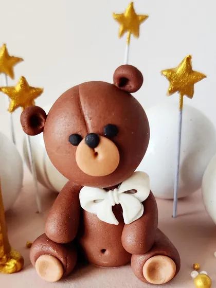 A detailed shot of the adorable fondant teddy bear topper, complete with a tiny white bow.