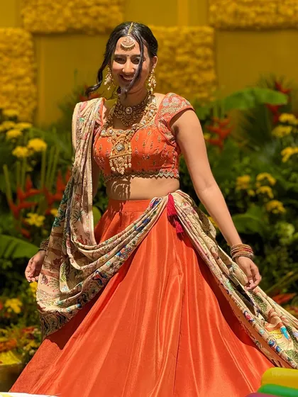 This vibrant orange silk lehenga shows how I play with color and traditional motifs. The skirt features a hand-painted border, paired with a Kashmiri embroidered blouse and a georgette dupatta, creating a joyful and elegant look for a mehendi or sangeet ceremony.
