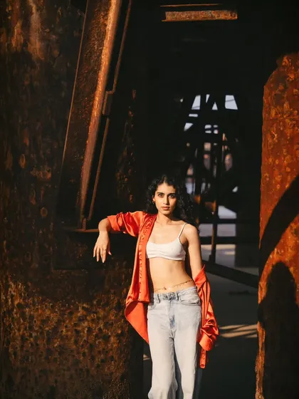 A full-body shot showing the contrast of the modern outfit against the old, weathered industrial background.