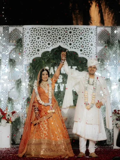 A triumphant moment after the wedding ceremony. The couple raises their hands in celebration, showered with confetti. This is the look of pure happiness and the start of a new journey.