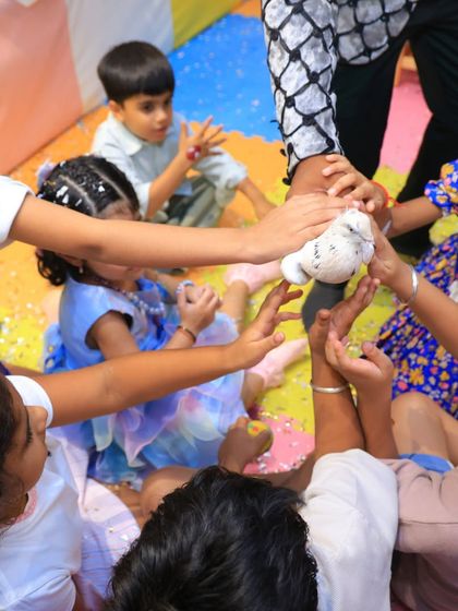 Children gently interact with a dove from the magic show. We ensure all animal interactions are safe, supervised, and positive for both the kids and the animals.
