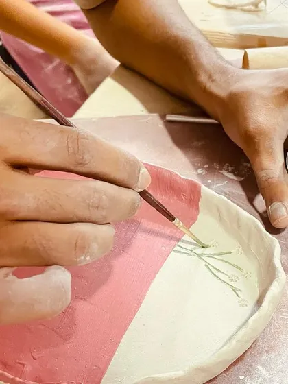 A student adds fine details to a painted plate, using a contrasting color to make the design pop.