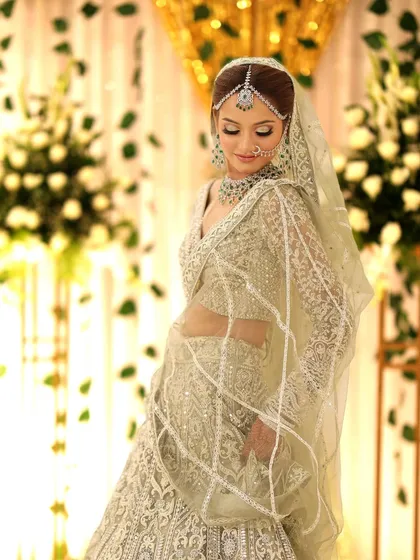 A graceful side profile of the bride in her white and silver lehenga. The diamond matha patti and necklace add a touch of modern royalty to her look.