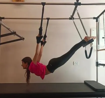 A client demonstrates incredible strength and control, hanging from the Cadillac. This is what we mean by self-care through movement.