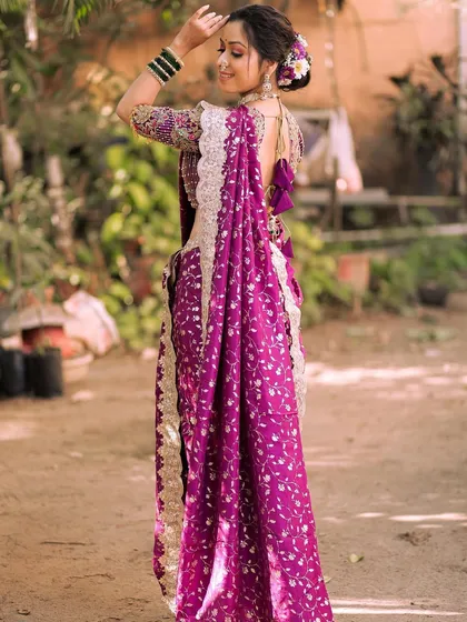 A beautiful shot from the back, showcasing the elegant drape of the purple saree and the intricate hairstyle. Every detail matters for the perfect bridal look.