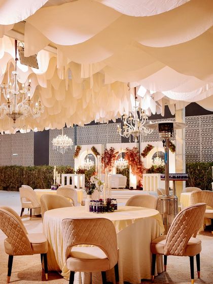 An elegant guest table at the reception, set under the beautiful white fabric ceiling and sparkling chandeliers.