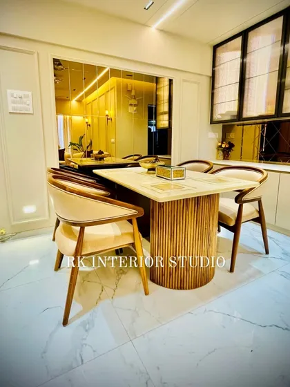 This is a beautifully designed dining area featuring a fluted-base table and comfortable chairs. The large mirror wall reflects the space, making it feel larger, while the custom crockery unit adds both storage and style.