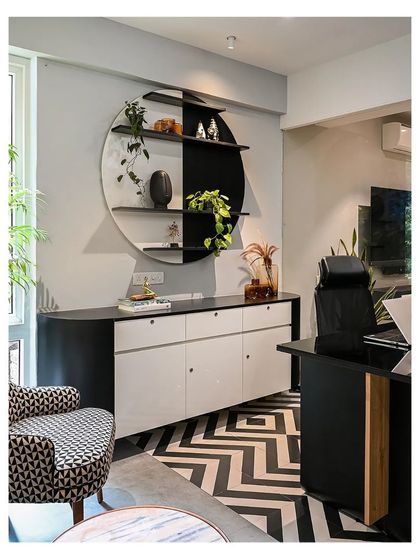 A custom circular shelf in black and white acts as a functional art piece in the manager's cabin, providing display space for plants and decor.