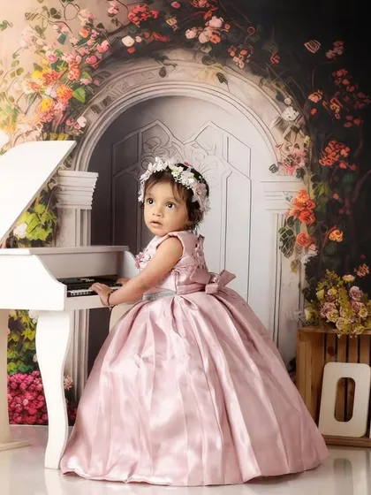 A little princess at her mini piano, dressed in a beautiful pink gown for her first birthday photoshoot.