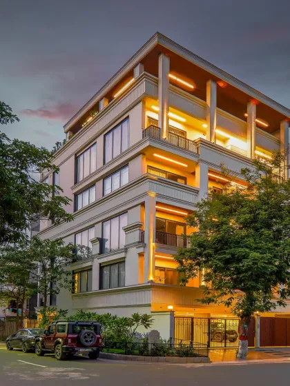 The Rosewood, Gurgaon facade at dusk. The architectural lighting highlights the classical details and the building's strong vertical lines, giving it a majestic presence on the corner plot.