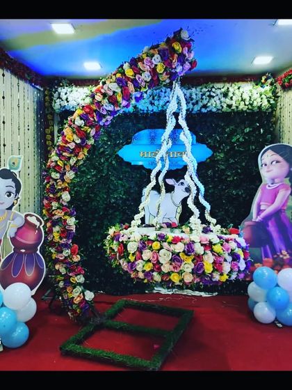 Another view of the Krishna-themed naming ceremony setup, showing the colorful floral cradle and backdrop, perfect for a home or small hall.
