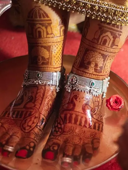 A close-up of bridal feet during a ceremony, adorned with traditional patterns and silver anklets. The design is both beautiful and symbolic.