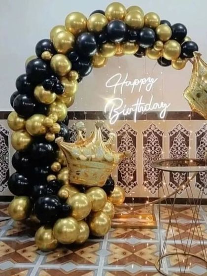 A royal-themed black and gold balloon arch with crown foil balloons.