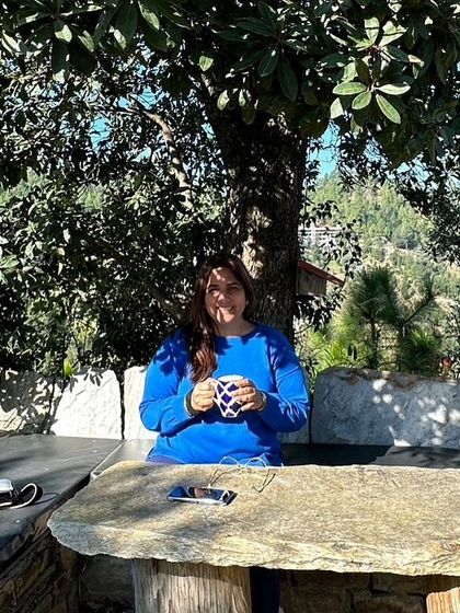 A participant enjoying a quiet moment with a cup of tea at one of our outdoor stone tables. The retreat is designed to offer spaces for both community and solitude.