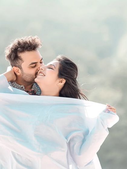 A playful and happy moment, with the couple laughing and wrapped in a white sheet. This captures their fun-loving spirit.