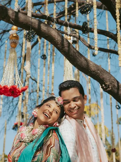 A moment of pure, unadulterated happiness. This candid shot of the couple laughing together under a decorated tree perfectly captures the spirit of their Haldi day.