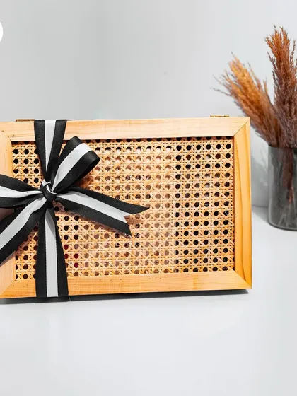 A sophisticated groomsman hamper in a stylish cane and wood box, tied with a classic black and white striped ribbon.