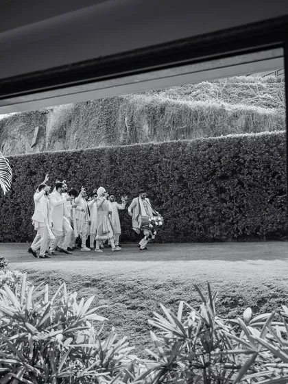 A black and white shot of a baraat procession. For 7 years, we've believed in instinct and heart, pouring our soul into every detail, from the grandest procession to the smallest gesture.