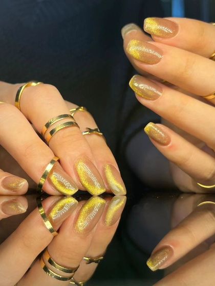 A side view of the golden-yellow cat-eye nails, highlighting their shimmer.