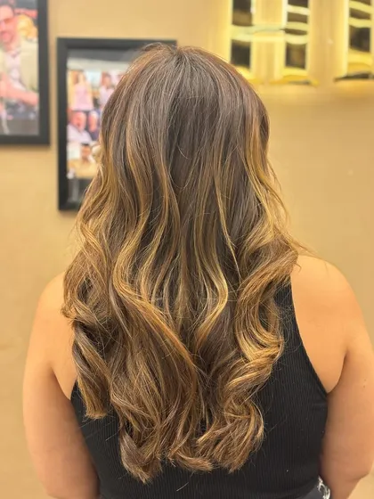 The back of a client's hair, showcasing a beautiful balayage with soft waves that add volume and movement.