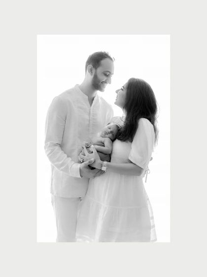 Love at first sight. A classic black and white portrait of a new family, their faces filled with joy and wonder as they hold their newborn. This is a timeless newborn photography moment.