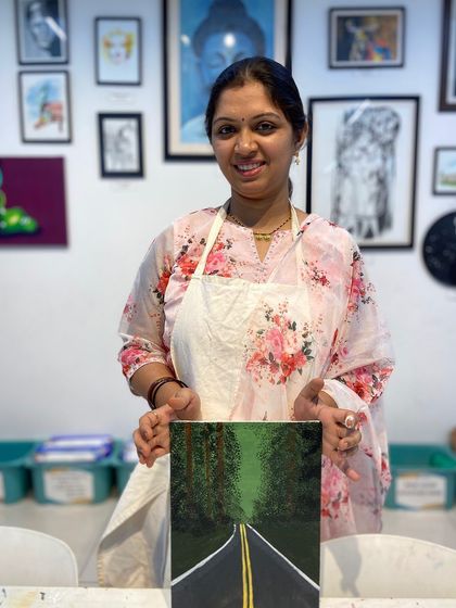 A participant with her finished canvas painting of a road disappearing into a forest. My workshops guide you through creating beautiful and atmospheric landscapes.