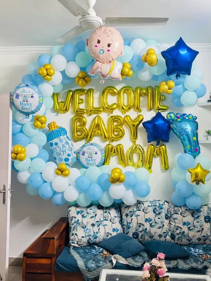 A 'Welcome Baby Mom' wall decoration with a cloud of blue and white balloons and lots of cute, baby-themed foil balloons.