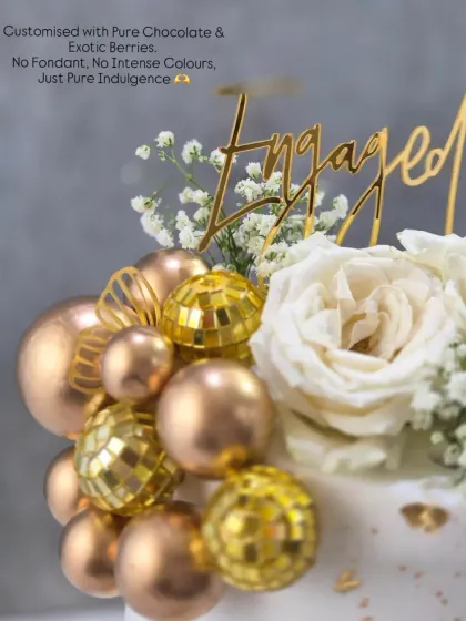 A close-up of the engagement cake's details, showing the golden disco balls, fresh white roses, and the "Engaged" topper.