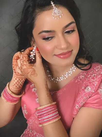 I love capturing these getting-ready moments. This image highlights the details of a pre-wedding look, from the soft pink makeup and delicate pearl necklace to the beautiful henna on her hands. It’s a simple, elegant style perfect for a ring ceremony.