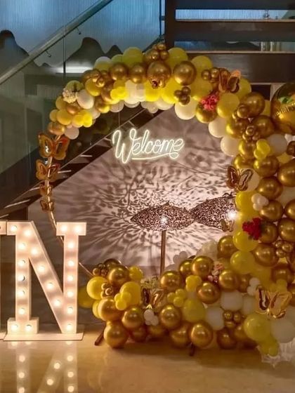 Another view of the elegant yellow and gold welcome decoration. The combination of the balloon arch, neon sign, and large light-up letters creates a stunning visual impact for an evening event.