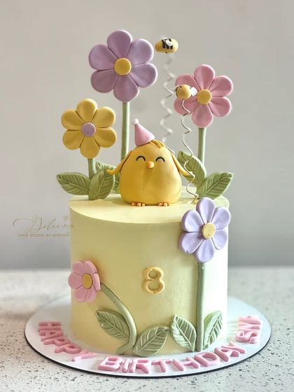Hello little duckling. This cheerful cake features a cute chick with a party hat, surrounded by fondant flowers and buzzing bees.