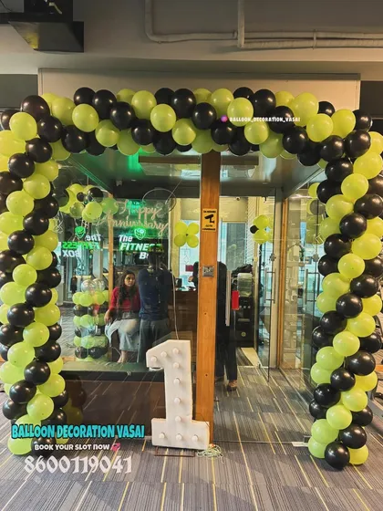 This is a full entrance balloon arch I designed for a gym's first anniversary. The energetic lime green and black color scheme matches the brand, and the large light-up number '1' makes the milestone clear from a distance.
