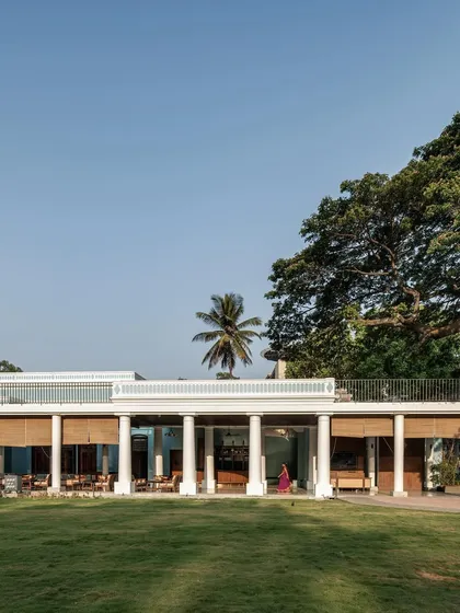 A wide view of the Bangalore Club project, showing how the new colonnade structure sits in harmony with the expansive main lawn and the majestic, mature trees that define the property's historic character.