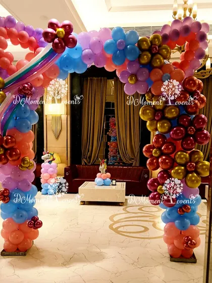 A unique and intricate balloon arch in the shape of a giant bow, incorporating rainbow and flower details to create a stunning entrance for a unicorn-themed party.