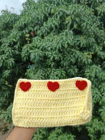 A sunny yellow pouch decorated with three small red hearts. It's a sweet and simple design that adds a pop of color.