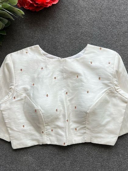 The front of the white Elzara silk blouse, featuring a simple, elegant design with scattered buti work.