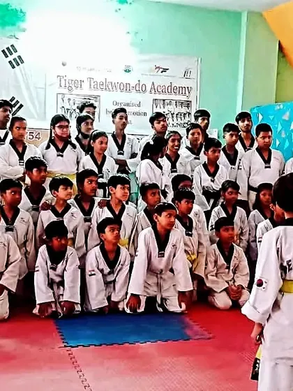 A full class of students listening attentively during a belt grading test event at the academy.