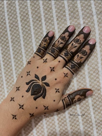 A striking minimalist design with a large lotus flower on the back of the hand, surrounded by small stars and dots. The fingers have matching lotus bands.