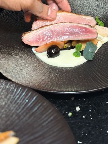 Placing slices of perfectly pink duck breast onto the plate. This action shot shows the final assembly of my Magret of Duck dish.