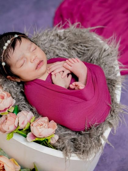 Infinite love in its tiniest form. This baby, swaddled in magenta and nestled in a bowl of flowers, shows how I combine classic wrapping with beautiful props.