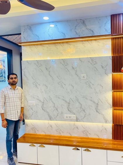 Proudly standing by the completed TV unit, a design that is both functional and a beautiful centerpiece for the living room.