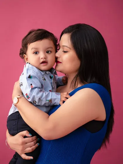 A mother's kiss. This close-up shot against the bold magenta background focuses on the tender connection between mother and child.